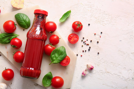 Board with glass bottle of ketchup and tomatoes on white background