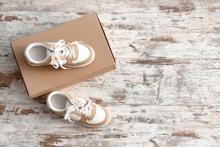 Cardboard box with stylish sneakers on light wooden backgroundの写真素材