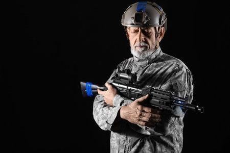 Ukrainian soldier with assault rifle on dark backgroundの写真素材