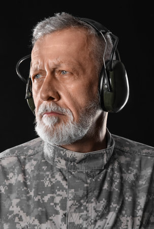 Mature soldier in headphones on dark background, closeupの写真素材