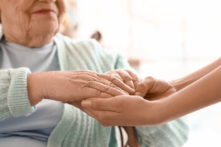 Senior woman with her granddaughter holding hands at home, closeupの写真素材