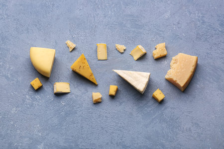 Pieces of tasty cheese on gray background