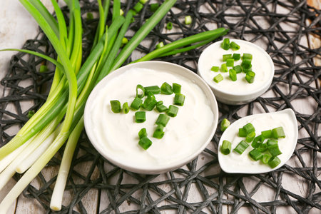 Bowls and gravy boat of tasty sour cream with sliced green onion, closeupの写真素材