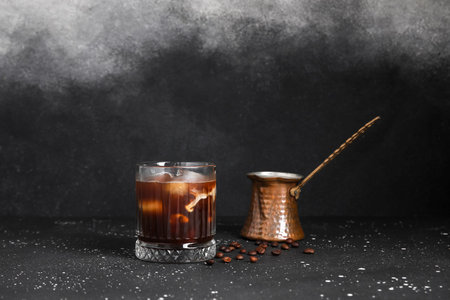 Glass of tasty ice coffee with milk and cezve on grunge background