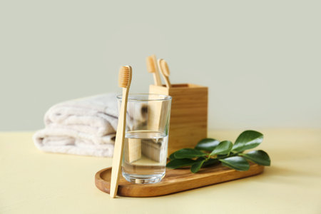 Bamboo toothbrush and glass of water in bathroomの写真素材