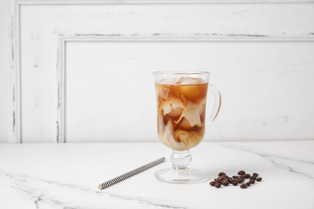 Glass cup of tasty ice coffee with milk on table
