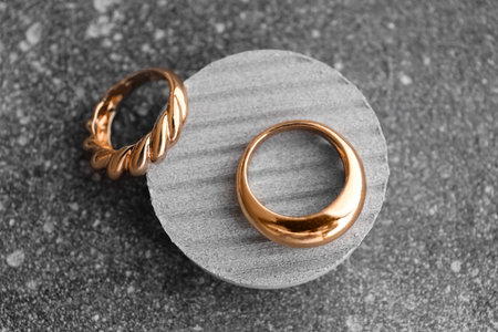 Decorative podium with beautiful golden rings on grunge gray background