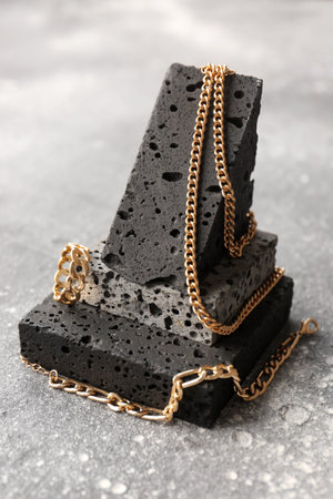 Decorative podium with beautiful jewelry on grunge gray background