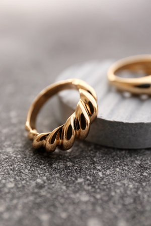 Decorative podium with beautiful golden rings on grunge gray background