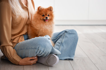 Mature woman with Pomeranian dog in kitchen, closeupの写真素材