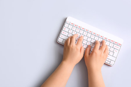 Female hands with modern computer keyboard on light backgroundの写真素材