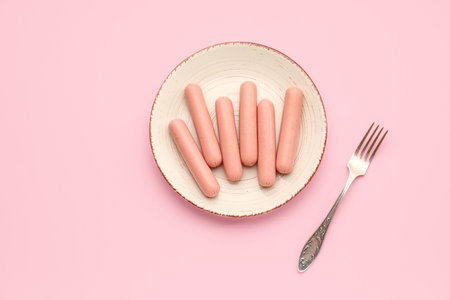 Plate with tasty thin sausages on pink backgroundの写真素材