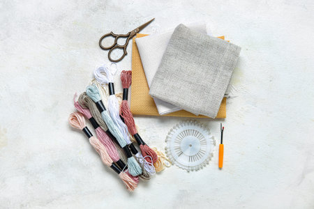 Different canvases with scissors, mouline threads and ball pins on grunge white background