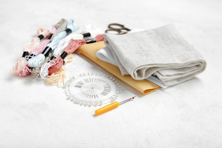 Different canvases with scissors, mouline threads and ball pins on grunge white background