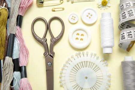 Set of different embroidery supplies on pale yellow background
