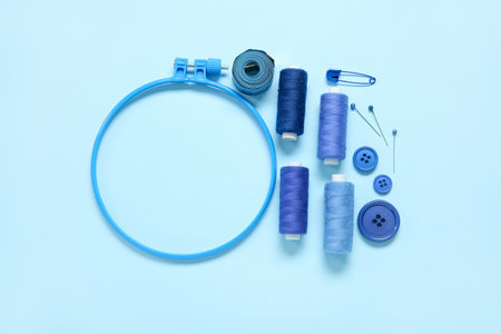 Embroidery hoop with thread spools, buttons and measuring tape on blue backgroundの写真素材