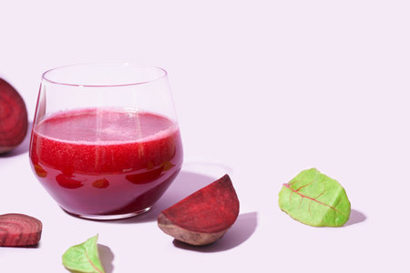 Glass of healthy beet juice and spinach on lilac backgroundの写真素材