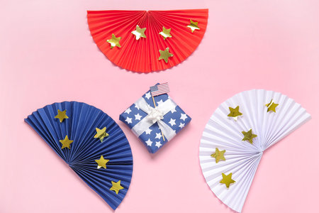 Gift box with USA flag and colorful fans on pink background. american independence day
