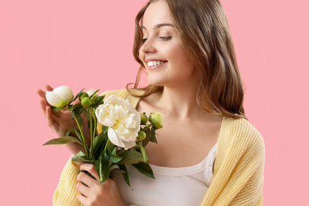 Beautiful young woman with bouquet of peony flowers on pink backgroundの写真素材