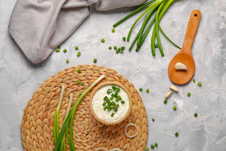 Bowl of tasty sour cream with sliced scallion and onion on gray backgroundの写真素材