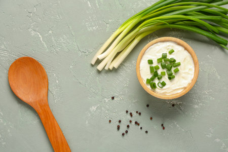 Bowl of tasty sour cream with sliced green onion and peppercorn on gray backgroundの写真素材