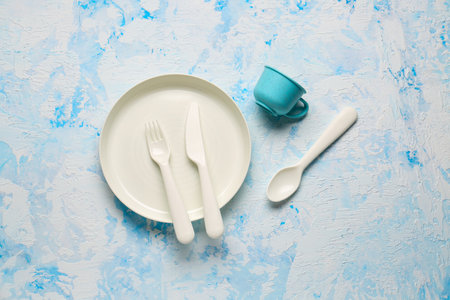 Plate with cutlery and cup for baby on grunge blue backgroundの写真素材