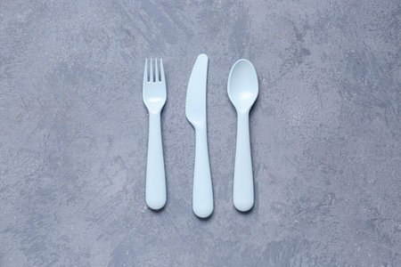 Plastic eating utensils for baby on grunge blue background