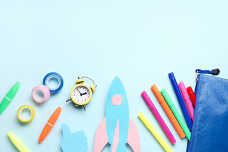 Paper rocket with pencil case and different stationery on blue backgroundの写真素材
