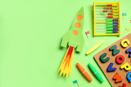 Paper rocket with abacus, wooden letters and stationery on green backgroundの写真素材