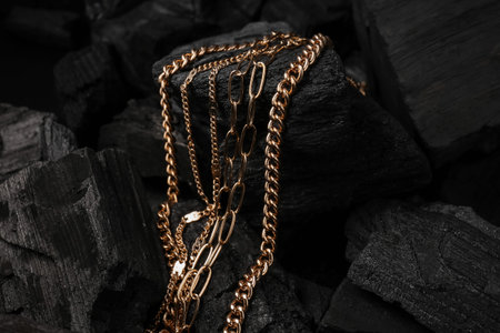 Beautiful chain necklaces on black charcoal, closeup