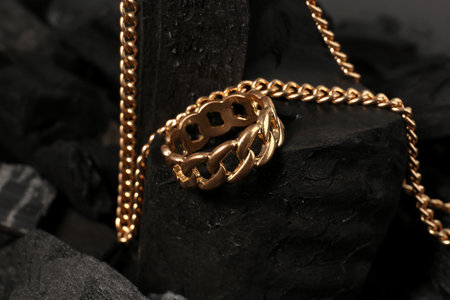 Beautiful chain necklace and ring on black charcoal, closeup