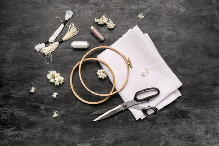 Embroidery hoops with canvas, mouline threads and scissors on grunge black background