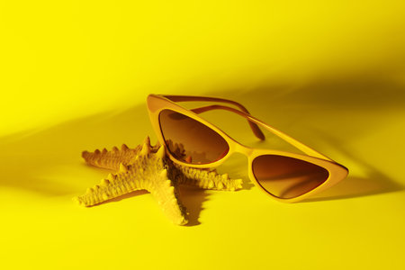 Stylish sunglasses with starfish on yellow backgroundの写真素材