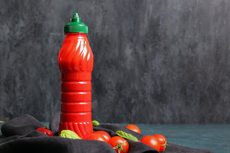 Bottle of ketchup and tomatoes on dark backgroundの写真素材