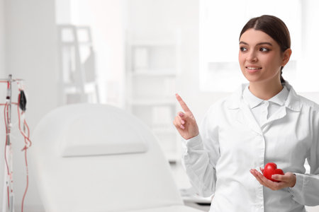 Female doctor with heart pointing at something in clinicの写真素材