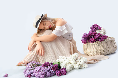Young woman with lilac flowers on light backgroundの写真素材