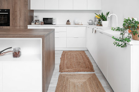 Wicker rugs on floor in interior of light kitchenの写真素材