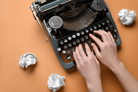 Woman typing on typewriter with crumpled paper on orange background