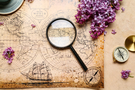 World map with compass, magnifier and lilac flowers on beige grunge backgroundの写真素材