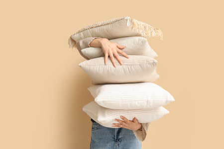 Woman with soft pillows near beige wallの写真素材