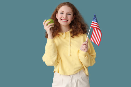 Young woman with USA flag and apple on blue backgroundの写真素材