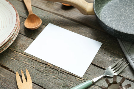 Blank card and different kitchen utensils on wooden background, closeupの写真素材