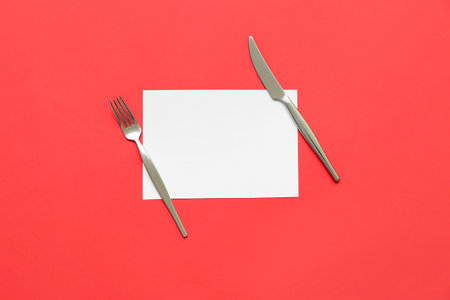 Blank card, stainless steel fork and knife on red backgroundの写真素材