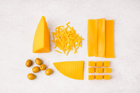Composition with pieces of tasty cheddar cheese and olives on white backgroundの写真素材