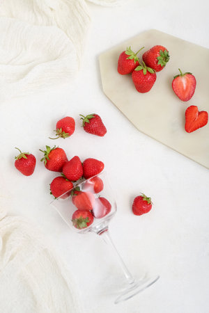 Glass and board with fresh strawberries on white backgroundの写真素材