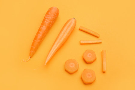 Fresh carrots and slices on orange backgroundの写真素材