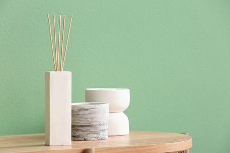 Bottle of reed diffuser and decor on table near color wall in room