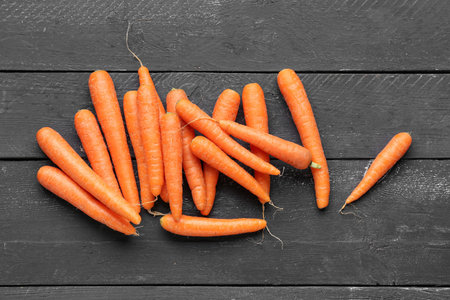 Many fresh carrots on black wooden background