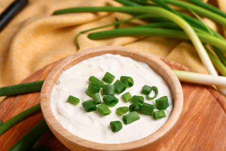Board with bowl of tasty sour cream and sliced green onion, closeupの写真素材