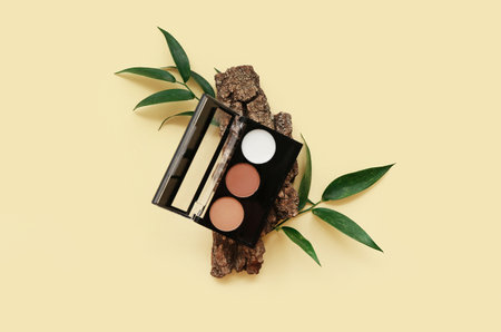 Composition with eyeshadows, tree bark and plant leaves on color backgroundの写真素材
